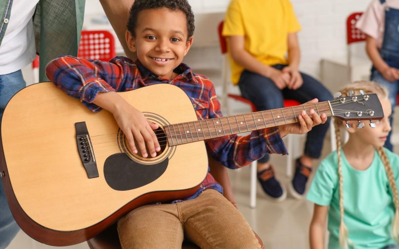Muziekles jongen op gitaar