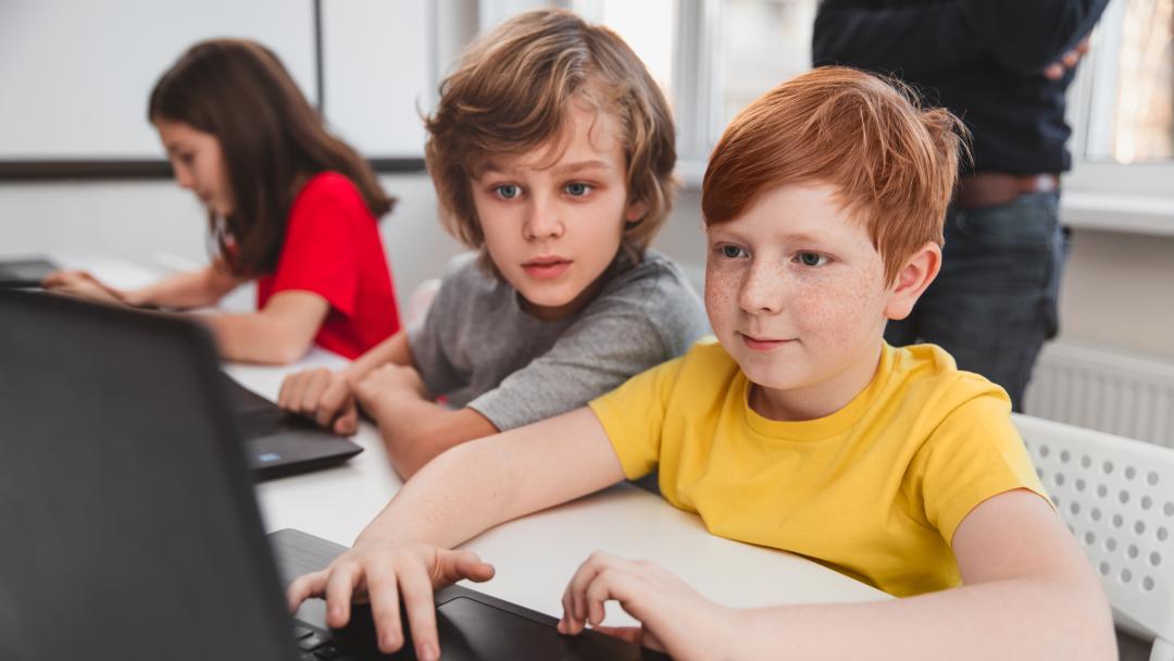 Twee kinderen werken aan een laptop